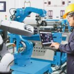 Engineer_using_laptop_computer_for_maintenance_automatic_robotic_hand_machine_tool_at_industrial_manufacture_factory