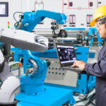 Engineer_using_laptop_computer_for_maintenance_automatic_robotic_hand_machine_tool_at_industrial_manufacture_factory