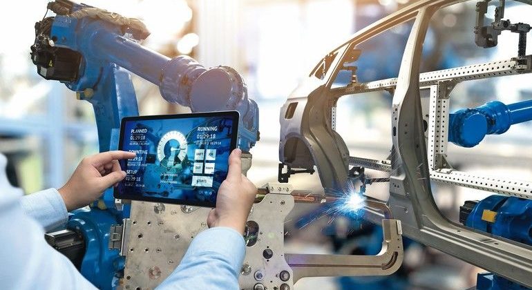 Engineer_hand_using_tablet_with_machine_real_time_monitoring_system_software._Automation_robot_arm_machine_in_smart_factory_automotive_industrial_Industry_4th_iot_,_digital_manufacturing_operation.