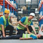 Warehouse_workers_first_aid_their_friend_after_accidents_or_First_aid_training_in_an_industrial_company,_safety_workplace_concept.