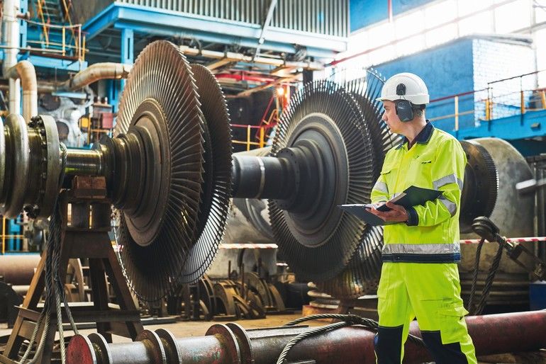 Power_plant_maintenance._Industial_worker_near_rotor_frome_turbine_at_electricity_production_station