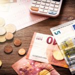Euro_banknotes_and_coins_with_bills_to_pay._Finances_and_budget_concept
