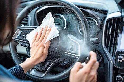 Hands_of_woman_uses_disinfectant_spray_on_steering_wheel_in_her_car