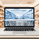 laptop_computer_on_wood_table_with_supermarket_aisle_blurred_background_online_shopping_concept