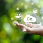 CO2_emission_reduction_concept_in_hand_with_environmental_icons,_global_warming,_sustainable_development,_connectivity_and_renewable_energy_green_business_background.