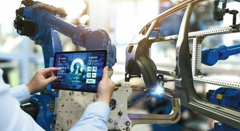 Engineer_hand_using_tablet_with_machine_real_time_monitoring_system_software._Automation_robot_arm_machine_in_smart_factory_automotive_industrial_Industry_4th_iot_,_digital_manufacturing_operation.