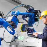 Engineer_using_labtop_computer_control_laser_robotic_cutting_on_metal_plate,_Industry_4.0_concept