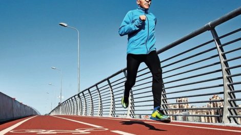 Low_angle_view_of_concentrated_senior_sportsman_jogging_outdoors_and_enjoying_sunny_warm_day,_full_length_portrait